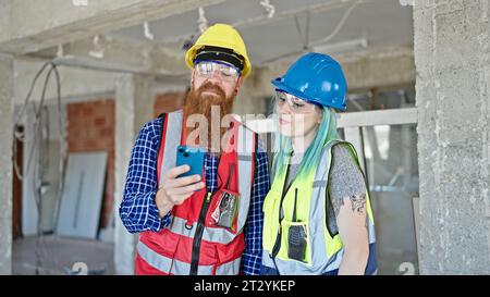 Man and woman builders using smartphone working at construction site Stock Photo
