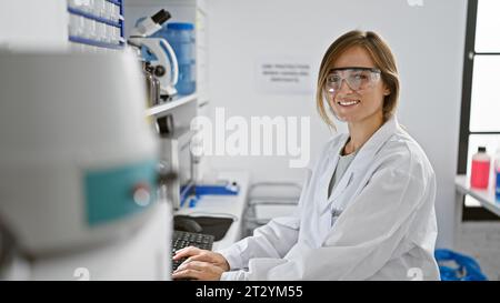 Young blonde woman scientist smiling confident using computer at laboratory Stock Photo