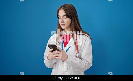 Young hispanic woman doctor using smartphone over isolated blue background Stock Photo