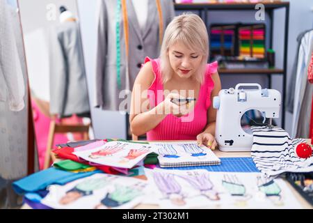 Young blonde woman tailor make photo by smartphone to clothing design at gaming room Stock Photo