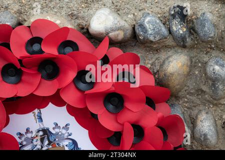 section of a poppy wreath leaning against a flint wall in Worthing, West Sussex, UK Stock Photo