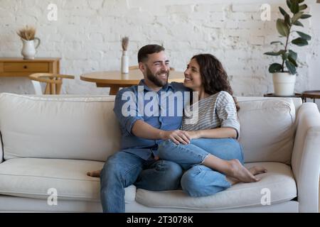 Joyful married couple relaxing on soft white home couch together Stock Photo