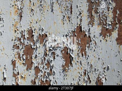 Grey metallic wall, background. Mangy surface with peeling and cracked paint on a rusty background. An old rusty surface with faded color and layers Stock Photo