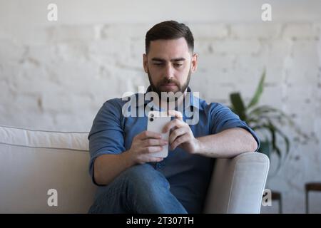 Serious thoughtful smartphone user man typing, reading message on cell Stock Photo