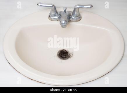 Nasty human hair in clean sink metal drainage close up view Stock Photo