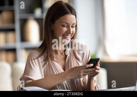 Smiling woman holding smart phone using on-line entertaining services Stock Photo