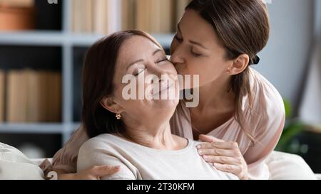 Loving adult daughter kisses her middle-aged mother on cheek Stock Photo