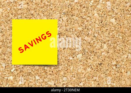 Yellow note paper with word savings on cork board background with copy space Stock Photo