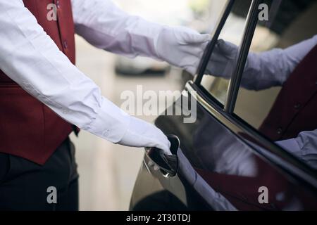 Close-up of doorman opening the door of the car and meeting the guest Stock Photo