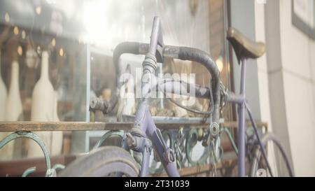 Vintage bicycle with chain at store. Action. Antique bicycle stands at window of store. Old rusty bicycle stands outside building on sunny day Stock Photo