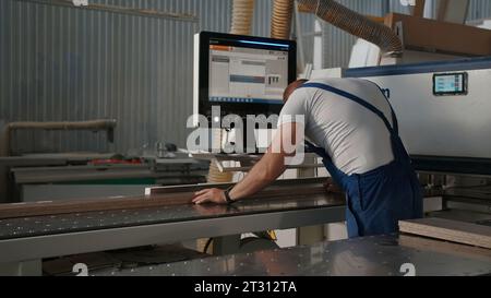 Delhi, India - April 29, 2023: woodworking machineries. Creative. Carpentry factory with a worker and wooden boards processing machine. Stock Photo