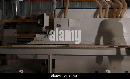 Delhi, India - April 29, 2023: woodworking machineries. Creative. Carpentry factory with a worker and wooden boards processing machine. Stock Photo