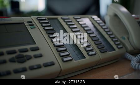 Landline phone at the factory workshop. Clip. Close up of a man hand pressing buttons on a stationary push button telephone. Stock Photo