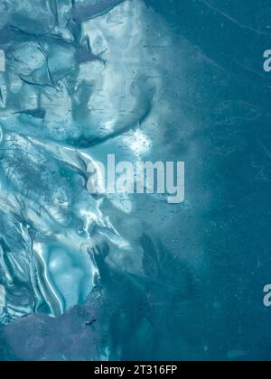 Texture of frozen ice of a mountain lake. The thickness of green-blue ice through which light is visible Stock Photo