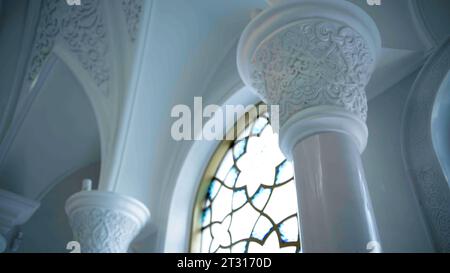 Carved elements on white columns inside white temple. Scene. Carvings on walls and ceiling. Stock Photo