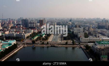 Summer cityscape and a wide river flowing along the buildings. Stock footage. Aerial view of a summer cityscape. Stock Photo
