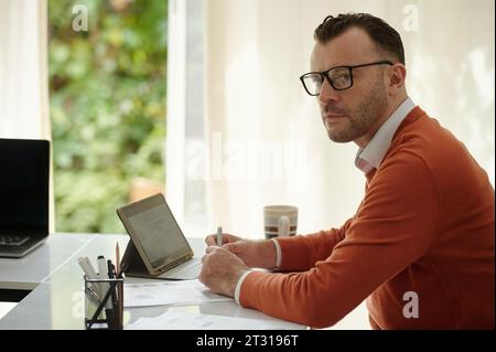 Portrait of entrepreneur in glasses working with documents at his office desk Stock Photo