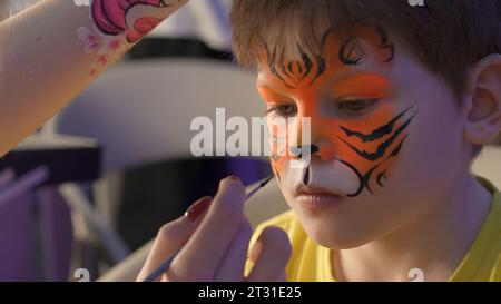 Serbia, Belgrade - June 20, 2023: Drawing on children's faces. Clip. Boy is sad if while he is being applied grimm. Drawing on faces with children for Stock Photo