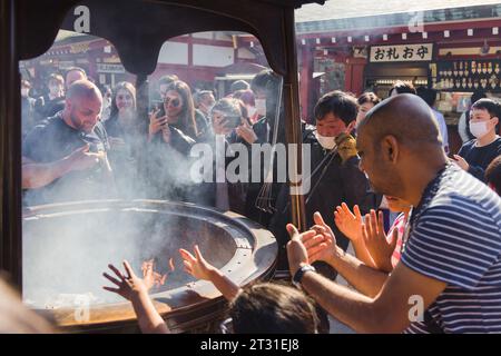 Tokyo, Japan - April 09, 2023: unidentified people at a traditional Jokoro at Senso-Ji Temple, Believers allow themselves to be surrounded by smoke at Stock Photo