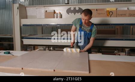 Delhi, India - April 29, 2023: Work in a factory. Stock footage. Workaholics in special clothes make furniture and boards with the help of special Stock Photo