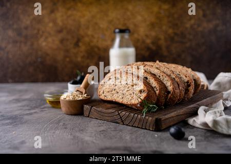 Baked sourdough bread from whole grain flour and pumpkin seeds on a grid, olive oil and black olive on a rustic wooden table. Artisan bread. Stock Photo