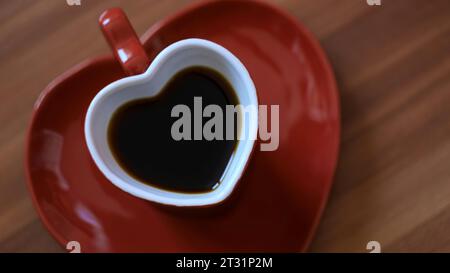 Man taking cup of coffee in shape of heart. Concept. Beautiful heart-shaped mug with coffee. Romantic mug with saucer in shape of heart with morning Stock Photo