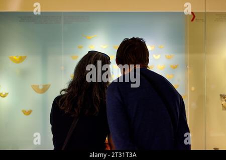 Bogota, Colombia - January 3, 2023: Couple of visitors look at the Zenu earmuffs in the Gold Museum Stock Photo