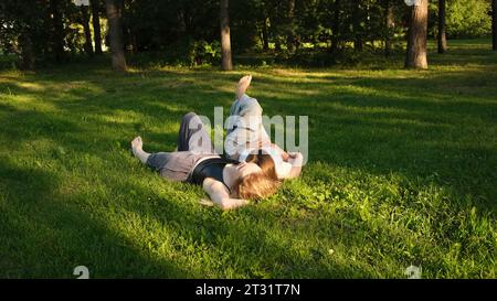 Friends are lying on green grass in park on sunny summer day. Concept. Beautiful girlfriends are lying on green grass in park. Relaxing in park on Stock Photo