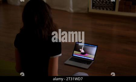 Woman using her laptop for doing yoga at home. Stock footage. Online classes of home exercises. Stock Photo