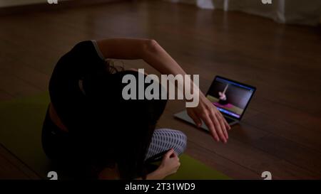 Woman using her laptop for doing yoga at home. Stock footage. Online classes of home exercises. Stock Photo