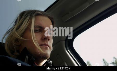 Low angle view of a man passenger inside car. Stock. Man with blond dyed hair looking worried and focused. Stock Photo