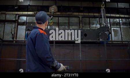 Worker controls remote control at factory. Clip. Worker moves large production parts using remote control. Remote control for moving loads of cables Stock Photo