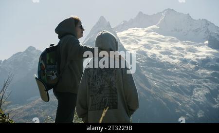 Family walk in the mountains. Creative. A young mother and son climbed to the top of the mountain and enjoy the sunny landscape. Stock Photo