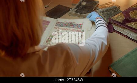 Woman flips through old book. Stock footage. Woman in gloves flips through old book. Old picture book in hands of restorer Stock Photo