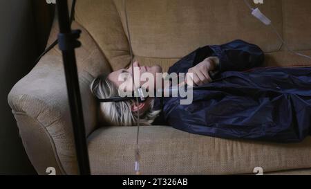 Young man commits suicide. Stock. Attack with convulsions in young man under drip. Young man on couch with gun and dropper commits suicide Stock Photo