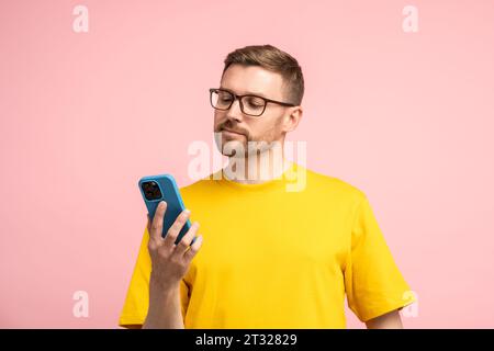Calm bearded man in glasses looking at mobile phone screen with composed settled satisfied face  Stock Photo