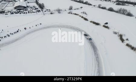 Bending winter ice track and driving cars during race. Clip. Winter sports race outdoors, drifting on ice. Stock Photo