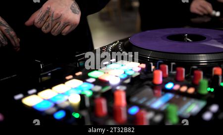 Berlin - Germany, december 6, 2022: Close up of a DJ console controlled by a man with tattooes on his fingers and hands. Art. Concept of electronic Stock Photo