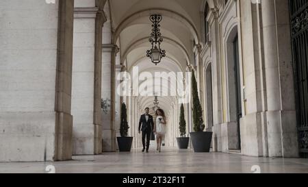 A walking couple of running newlyweds. Action. A large castle next to which people are running with flowers and happy faces in wedding dresses. Stock Photo