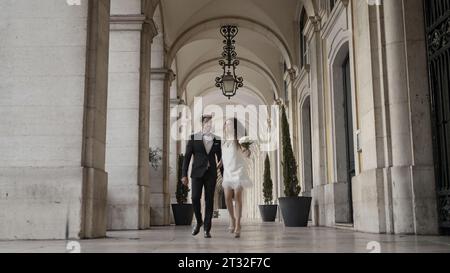 A walking couple of running newlyweds. Action. A large castle next to which people are running with flowers and happy faces in wedding dresses. Stock Photo