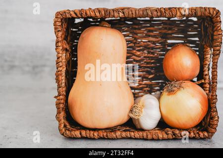 Butternut squash, galic, and onion in a basket, close-up on a rustic ...