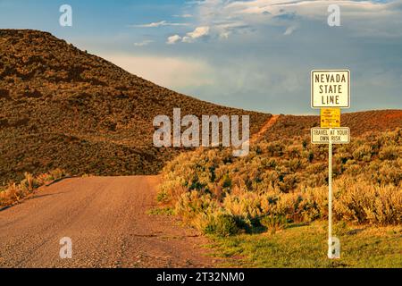 Sign on a dirt road in the Lassen County California high desert telling travelers that they are crossing the Nevada state line Stock Photo