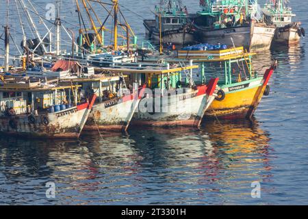 Commercial fishing boats anchored in calm waters at sunset with colorful reflections in the water Stock Photo