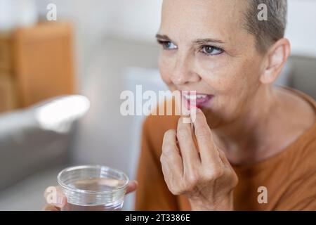 Caucasian woman sitting on the sofa and taking prescription pills prescribed Stock Photo