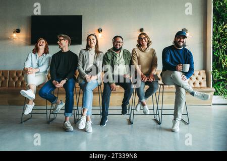 Group of business professionals sitting together in an office portrait, showcasing teamwork and collaboration. They are happy and smiling, demonstrati Stock Photo