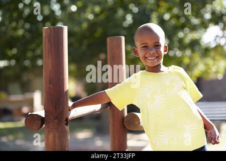 African boy, portrait and playground at kindergarten, outdoor and sunshine for playing, games and freedom. Child, school garden or park with smile Stock Photo