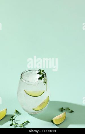 Lemonade or Detox Infused Water with Lime and Thyme, Cold Refreshing Summer Drink Gin Tonic on Green Mint Background Stock Photo
