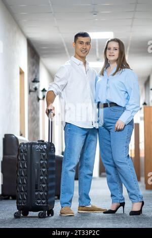 Young couple in hotel hallway get ready to check-in Stock Photo