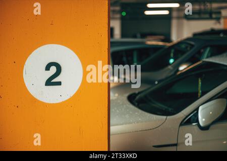 Number 2 on underground parking garage wall with cars in background, selective focus Stock Photo