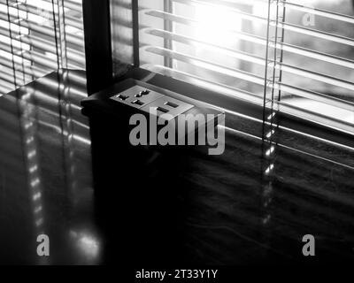 Black dual desk-mounted USB plugs and sockets on dark marble table near the window with louver, with copy space. Business technology concept. Outlet p Stock Photo